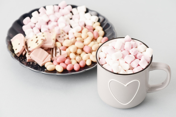 Mug of Marshmallows Stands Next to Plate of Sweets